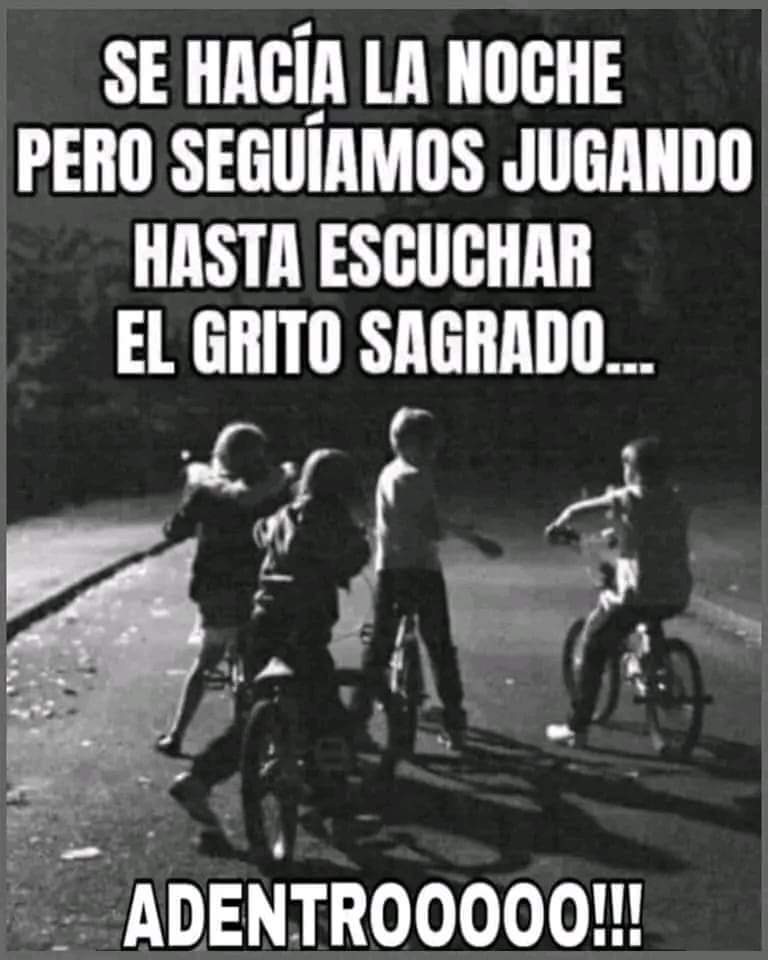 Foto en blanco y negro de cuatro niños con bicicletas en una calle al anochecer.