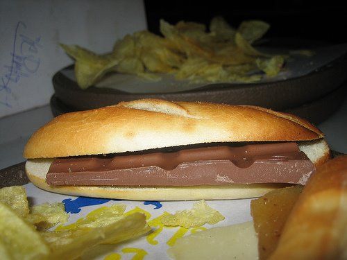 Bocadillo de pan con una tableta de chocolate dentro sobre una mesa.