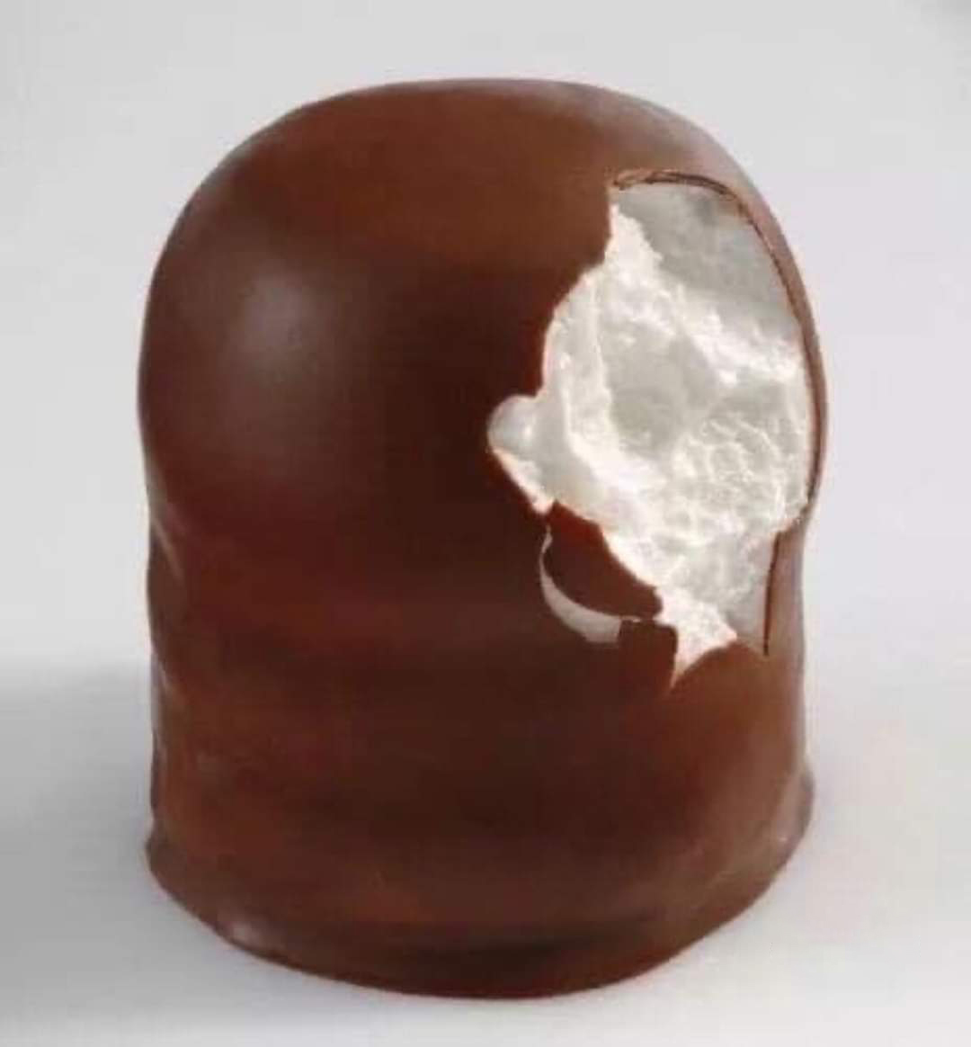 Bombón de chocolate mordido con relleno blanco de merengue.