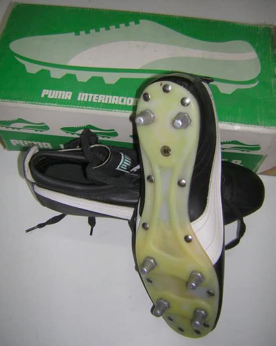 Botas de fútbol Puma con tacos metálicos junto a su caja.