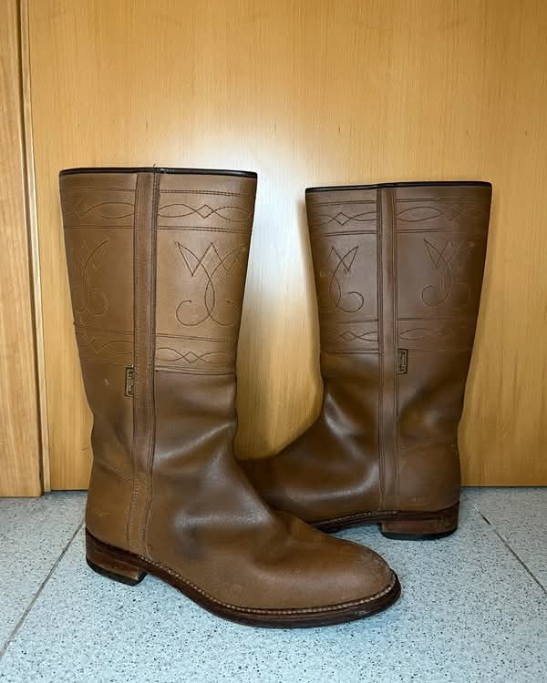 Par de botas camperas de piel marrón con pespuntes.