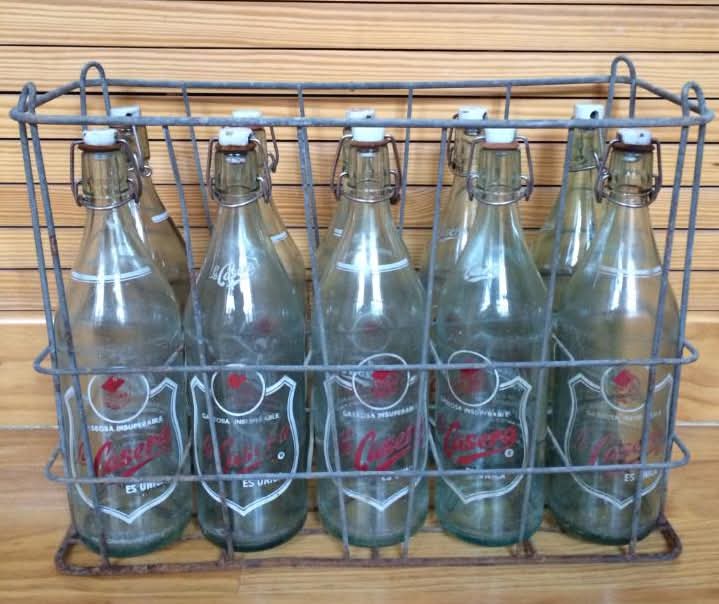 Cesta metálica con botellas de cristal retornables.