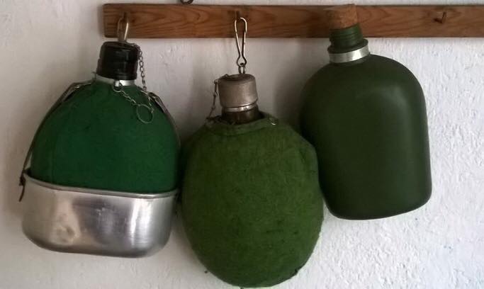 Tres cantimploras de fieltro verde colgadas.