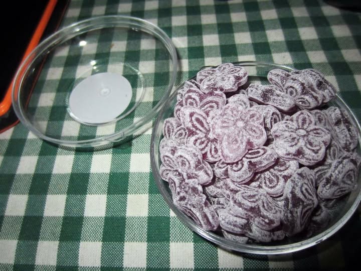 Cuenco de cristal lleno de caramelos morados con forma de flor.