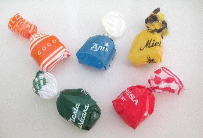 Seis caramelos envueltos en papeles de colores con los sabores coco, anís, miel, menta y fresa.