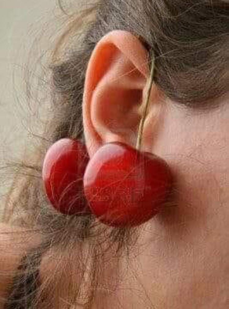 Oreja con dos cerezas colgadas como pendientes.
