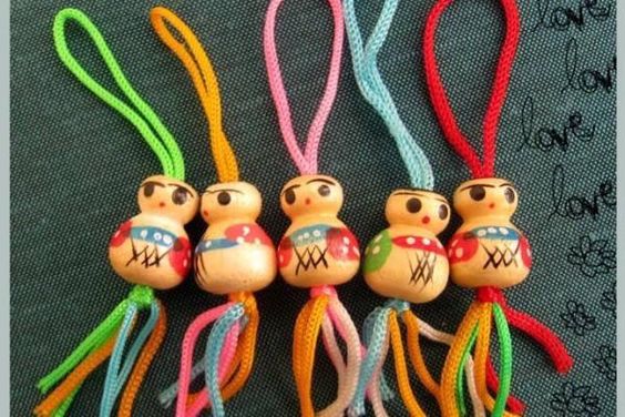 Muñequitos de madera con cordones de colores.