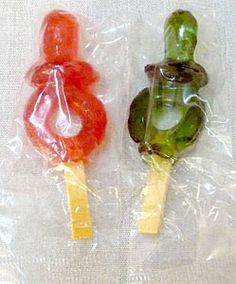 Dos piruletas con forma de chupete, una roja y una verde, envueltas en plástico.