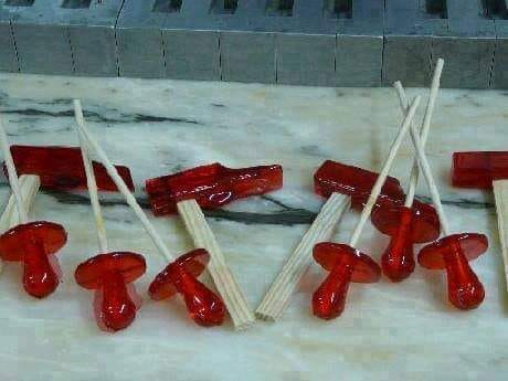 Piruletas rojas con forma de chupete y de martillo sobre mármol.