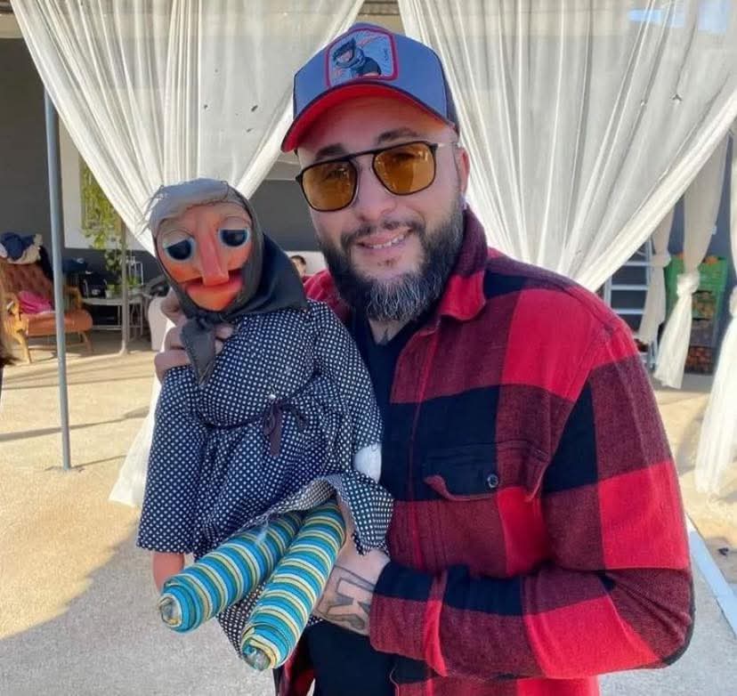 Hombre con gorra sosteniendo la muñeca Doña Rogelia