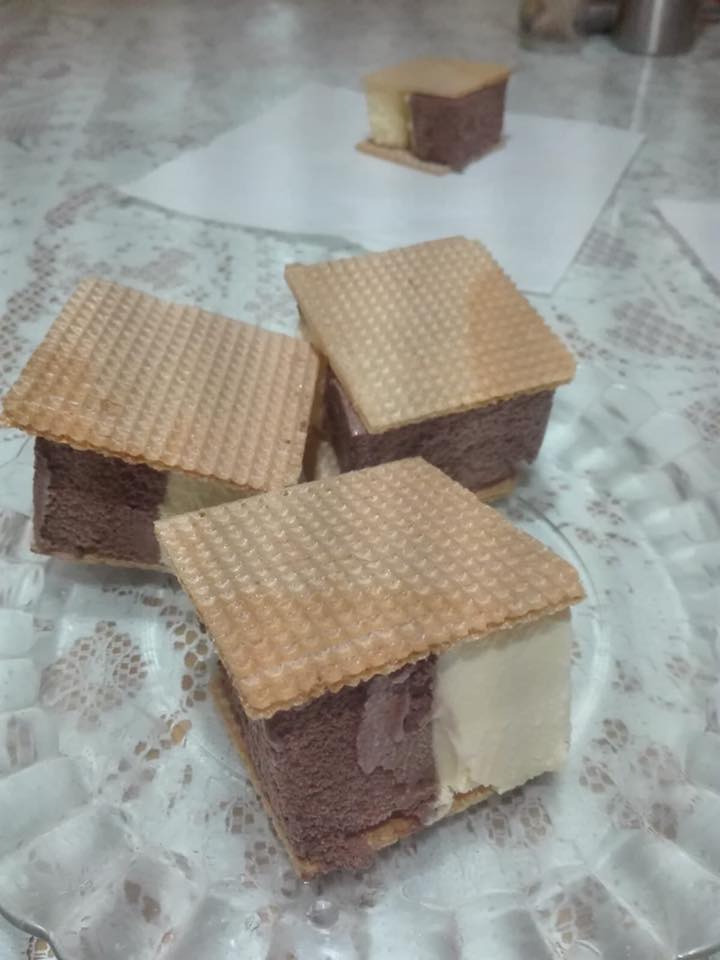 Tres cortes de helado de chocolate y nata entre galletas de barquillo.