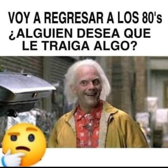 Doc Brown, con el pelo blanco, camisa de flores y chaqueta amarilla, sonriendo junto al DeLorean.