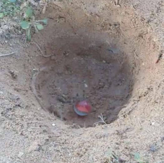 Agujero en la tierra con una canica en el fondo.