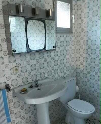 Cuarto de baño antiguo con azulejos estampados, lavabo y armario de espejo