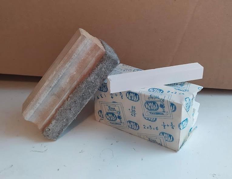 Borrador de pizarra junto a una caja de tizas