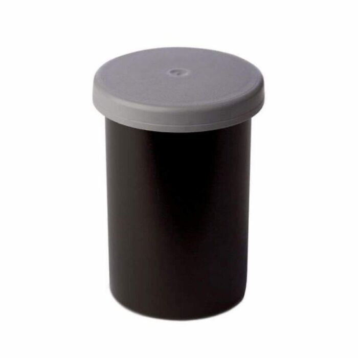 Bote negro de plástico con tapa gris de los que se usaban para guardar los carretes de fotos.