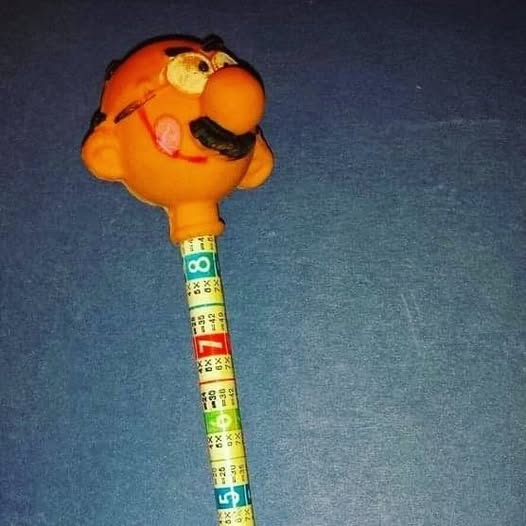 Lápiz con una cabeza de goma naranja de un hombre con bigote.