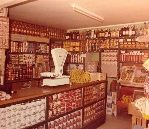 Interior de una tienda de comestibles con báscula y estanterías llenas
