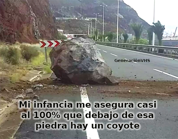 Gran roca caída en medio de una carretera junto a una montaña.