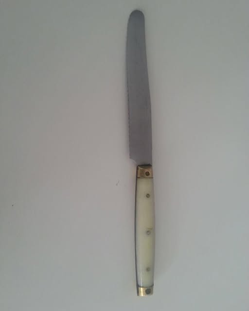 Cuchillo de mesa con mango blanco.