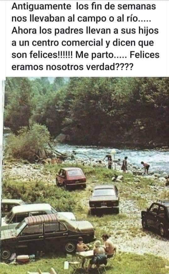 Foto antigua de coches de los 70 aparcados junto a un río, con familias comiendo en mesas plegables y gente en el agua.