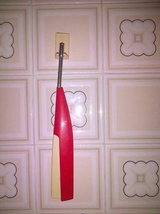 Encendedor de cocina rojo colgado en una pared de azulejos