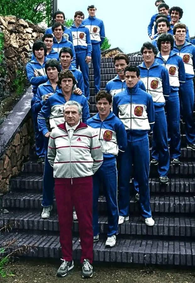 Equipo deportivo con chándal azul posando en una escalinata con su entrenador