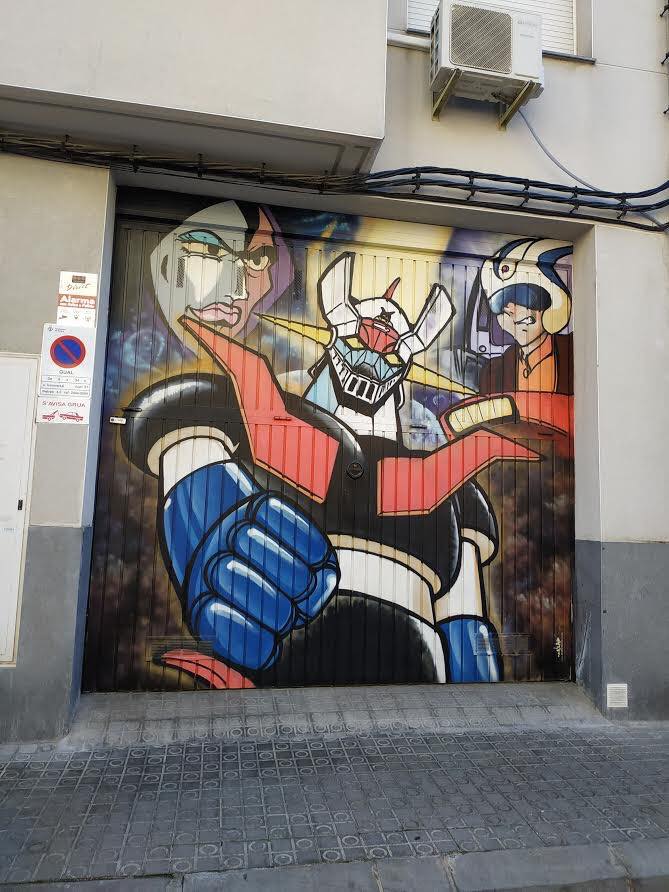 Puerta de garaje pintada con un gran grafiti de Mazinger Z y dos personajes de la serie.