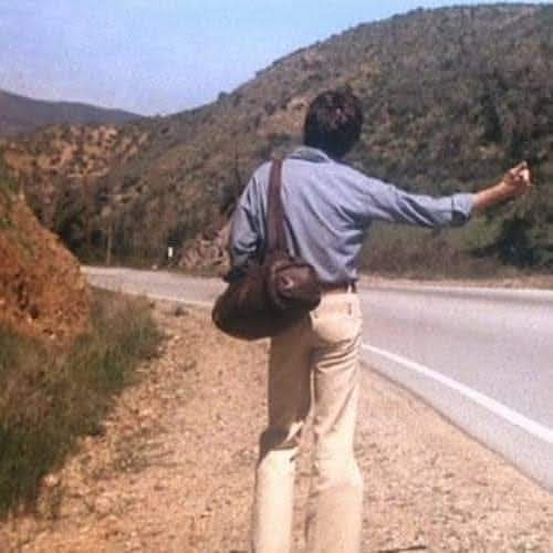 Hombre de espaldas haciendo autoestop en una carretera de montaña