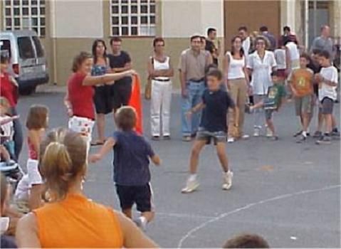 Niños jugando en una calle con adultos alrededor
