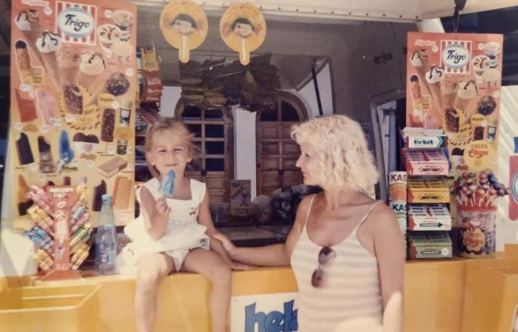 Niña sentada en el mostrador de un kiosco de playa lleno de juguetes