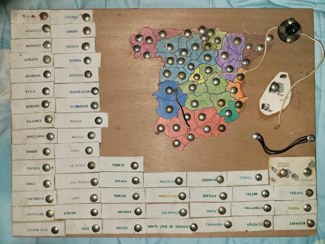 Mapa de España en madera con tornillos, cables y una bombilla para preguntas y respuestas