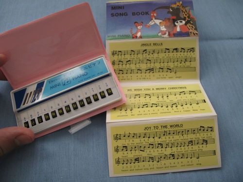 Minipiano de bolsillo rosa con un cancionero.