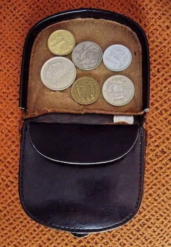 Monedero de piel negra abierto con monedas de pesetas