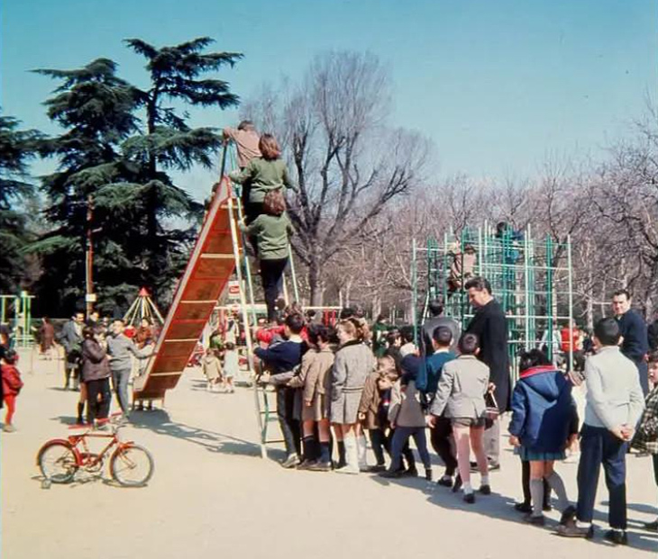 Muchos niños jugando en un parque con tobogán