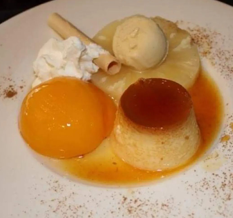Plato con flan, melocotón en almíbar, piña, bola de helado, nata y barquillo.