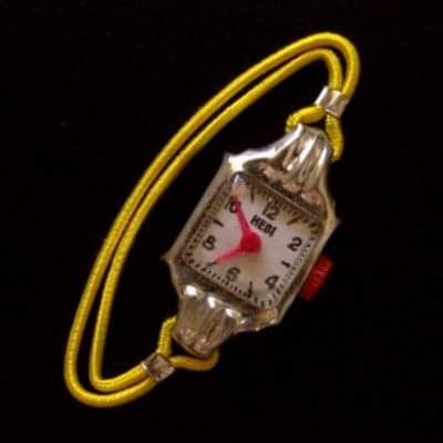 Reloj de juguete con correa elástica amarilla.