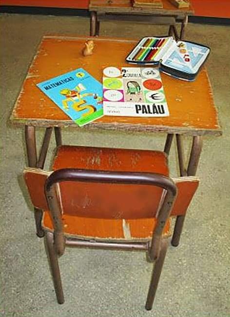 Pupitre de madera con libros escolares y una silla