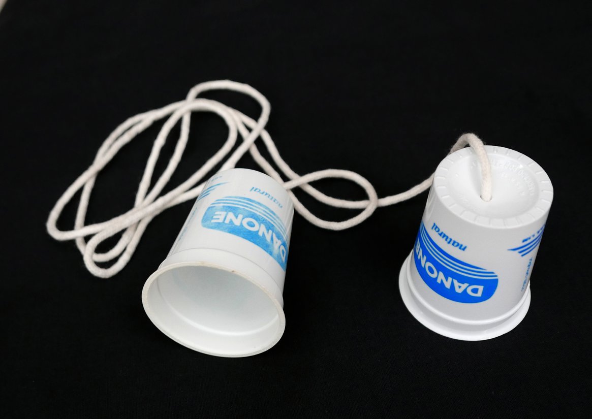 Dos vasos de yogur Danone unidos por un cordel blanco.