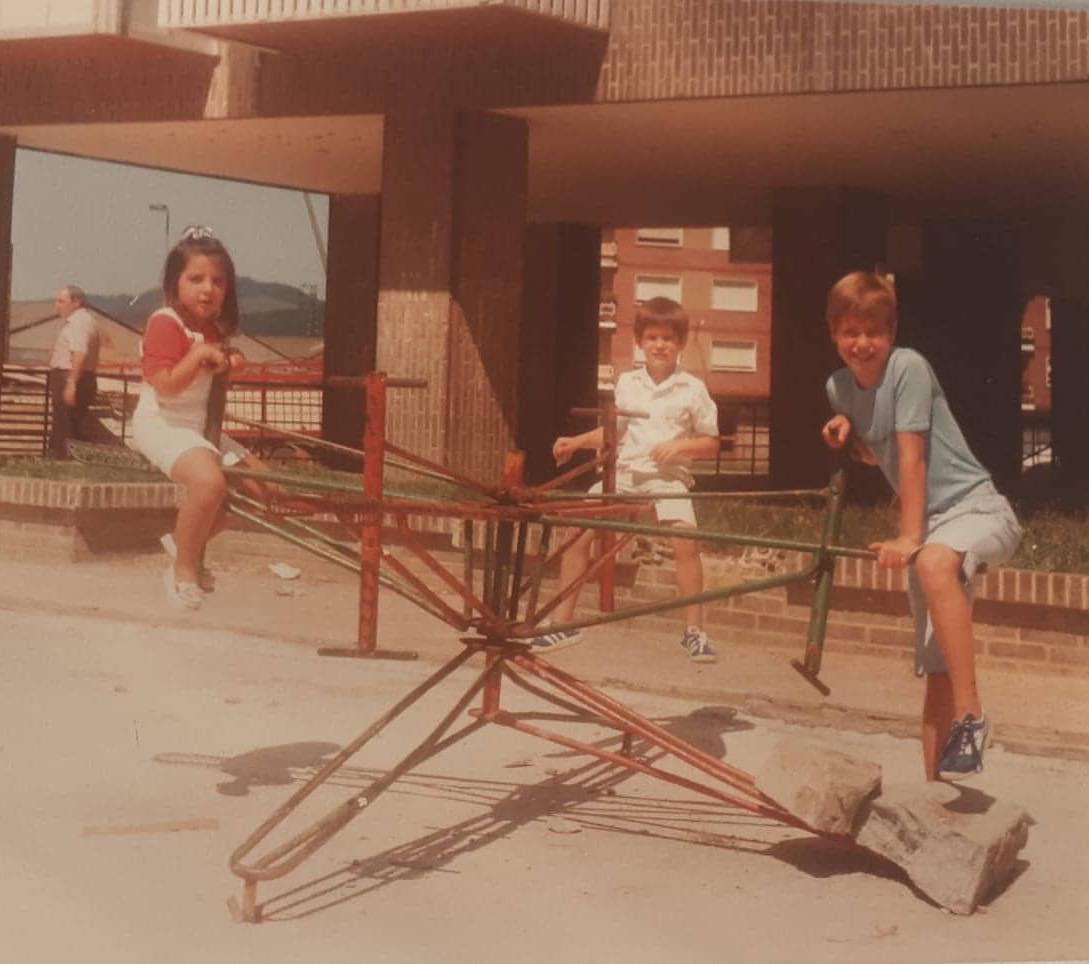 Niños subidos a un tiovivo de hierro en un parque