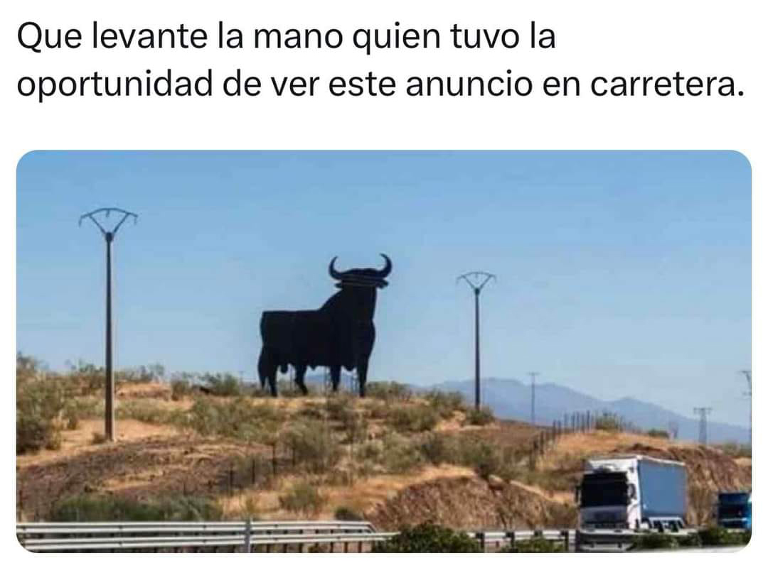 Silueta negra del toro de Osborne en una colina junto a una autovía con un camión.