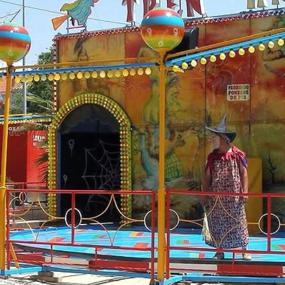 Atracción de feria El tren de la bruja con una bruja en la entrada.