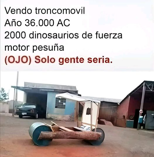 Coche casero hecho con dos bidones azules, un tronco y un techo de madera, aparcado en un patio.