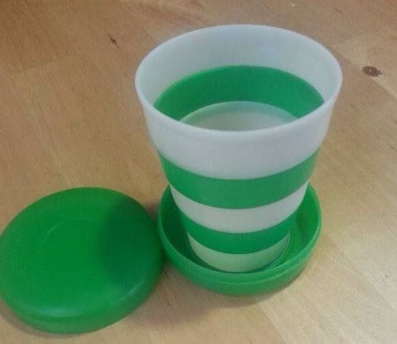 Vaso plegable de plástico verde y blanco con su tapa.