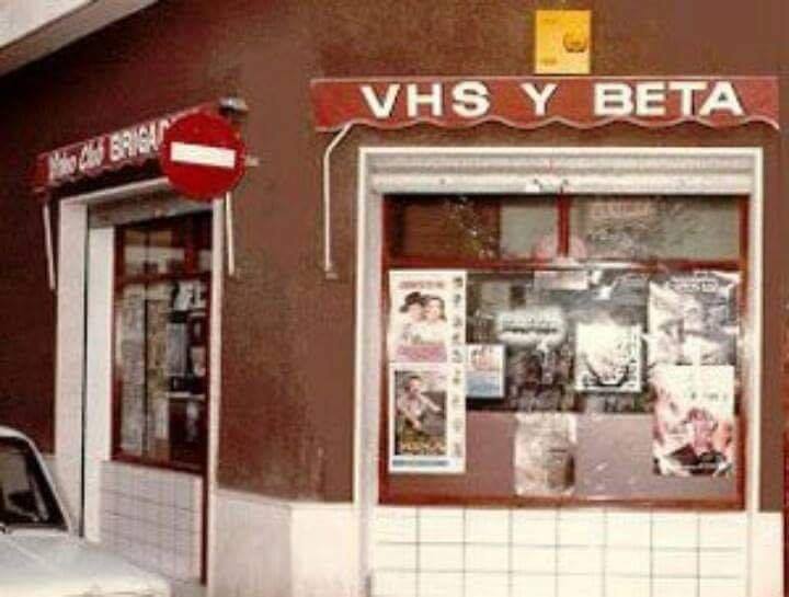 Fachada de un videoclub con el rótulo VHS y Beta y carteles de películas en el escaparate