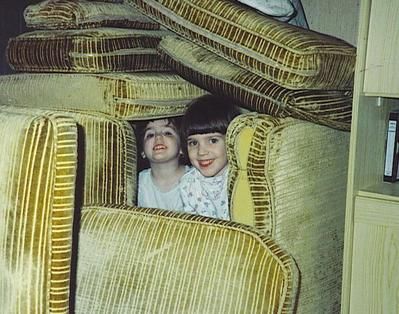 Dos niñas asomando entre cojines de un sofá