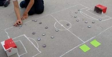 Campo de fútbol pintado con tiza en el suelo con chapas.