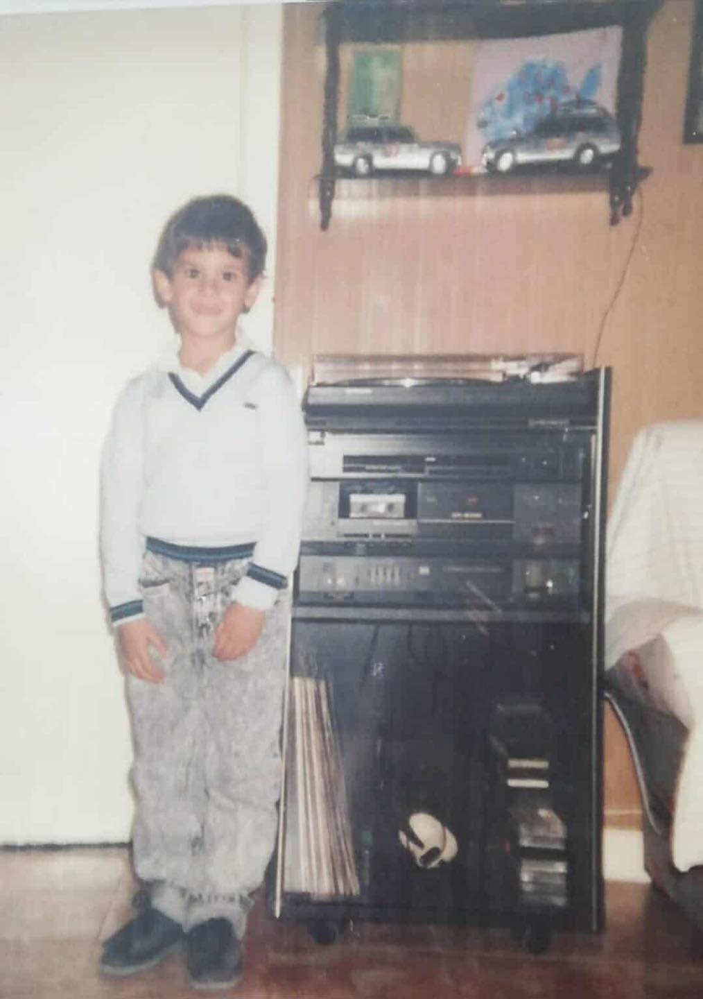 Niño posando junto a un equipo de música