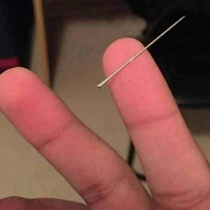 Aguja atravesando la piel de un dedo.
