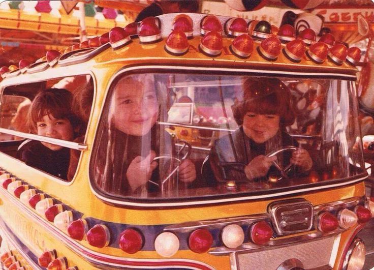 Niños dentro de un coche de una atracción de feria lleno de luces